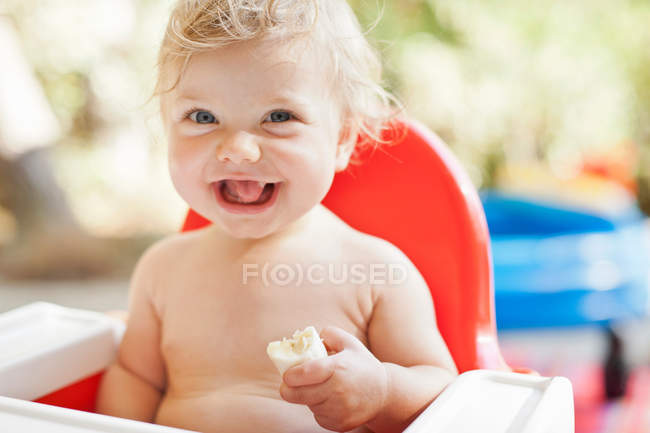 Сміється малюк їсть у високому кріслі — стокове фото