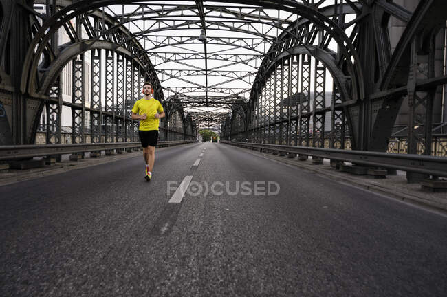 Jeune athlète masculin courir sur le pont — Photo de stock