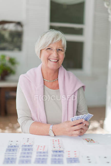 Улыбающаяся пожилая женщина играет в карты — стоковое фото