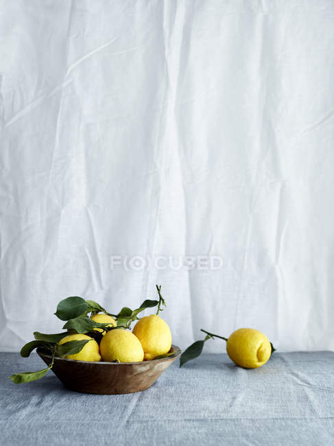 Чаша свіжих лимонів в миску на скатертину — стокове фото