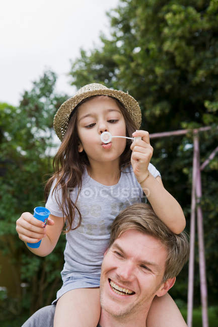 Girl with bubbles on fathers shoulders — Stock Photo