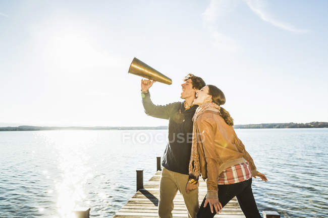 Casal usando megafone por lago — Fotografia de Stock