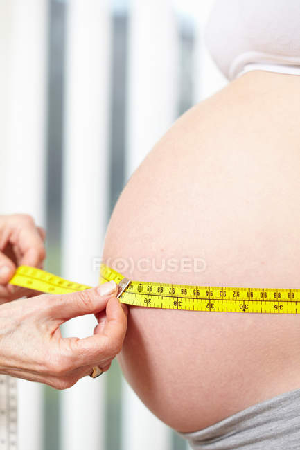 Manos que miden el vientre embarazada - foto de stock