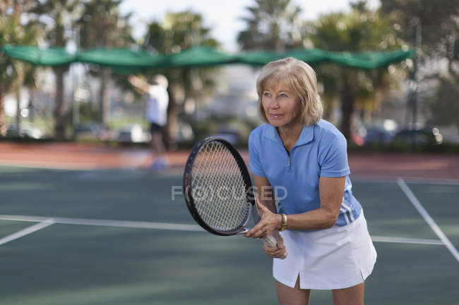 Donna anziana che gioca a tennis all'aperto — Foto stock