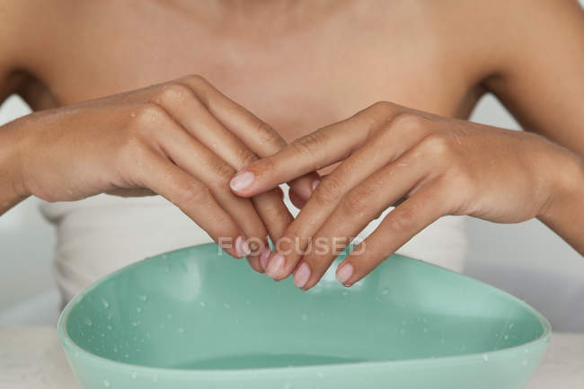 Las manos de la mujer en tazón de agua - foto de stock