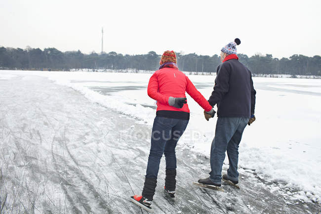 Couple ice skating, holding hands — Stock Photo