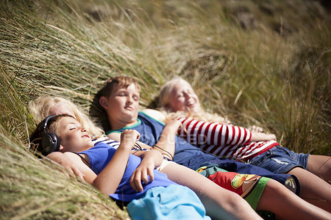Cuatro amigos relajándose en las dunas, Gales, Reino Unido - foto de stock