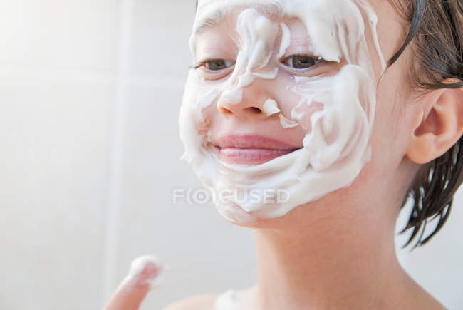 Girl rubbing moisturizer on her face — Stock Photo