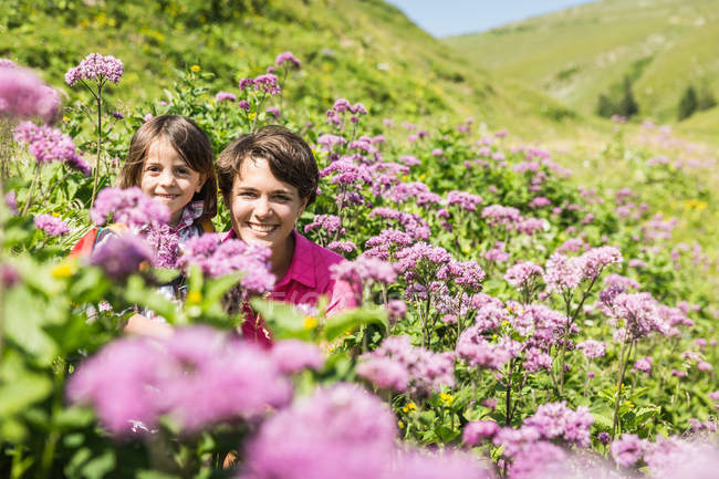 Madre e hija escondidas entre flores silvestres, Tirol, Austria - foto de stock