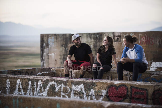 Giovani uomini e donne seduti su un muro di graffiti a miniera rovinata — Foto stock