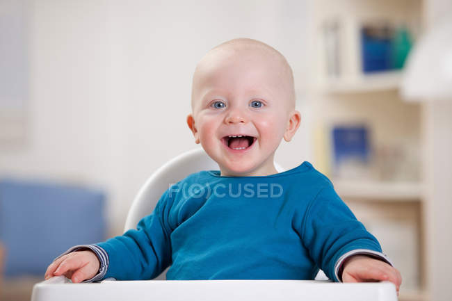 Smiling baby boy sitting in high chair — Stock Photo