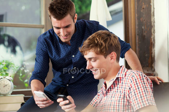 Dos hombres jóvenes usando teléfonos inteligentes - foto de stock