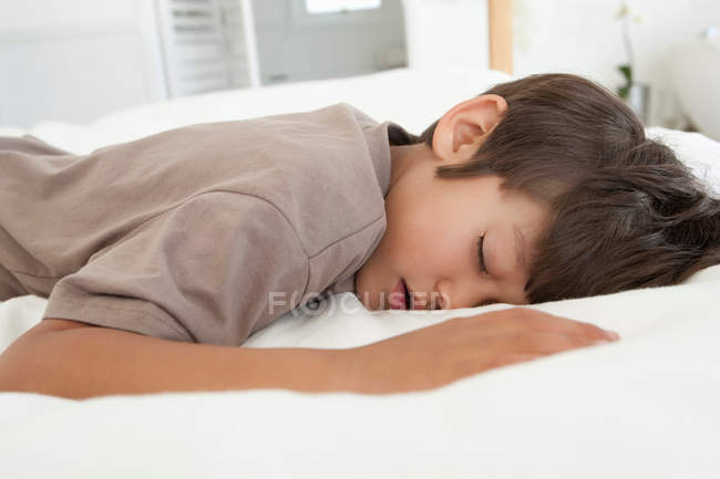Хлопчик спить на ліжку, фокус на передньому плані — стокове фото