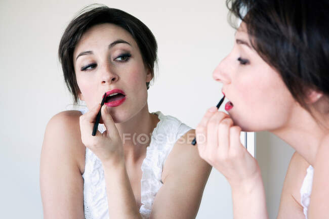 Woman applying lipstick in mirror — Stock Photo