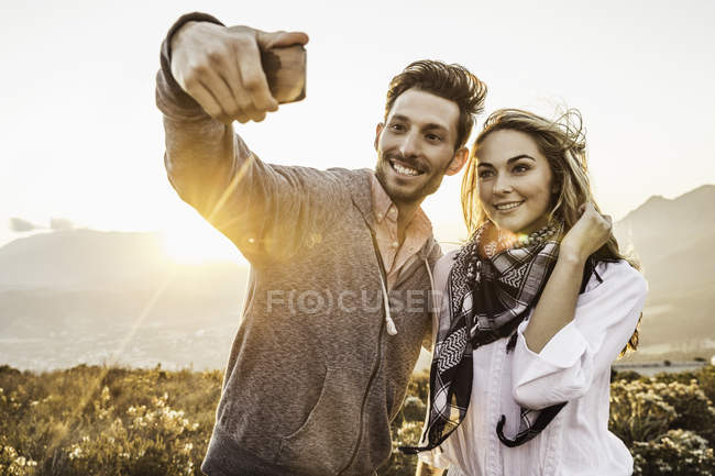 Coppia in collina prendendo selfie — Foto stock