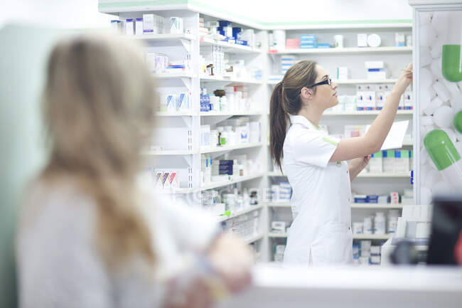Pharmacist getting medication from shelf — Stock Photo