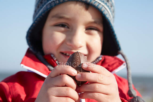 Rapaz sorridente com ovo de chocolate lá fora — Fotografia de Stock