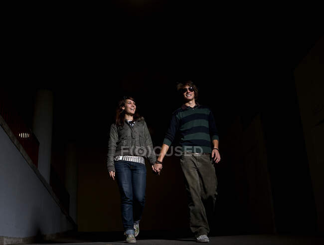Young couple holding hands in underpass — Stock Photo