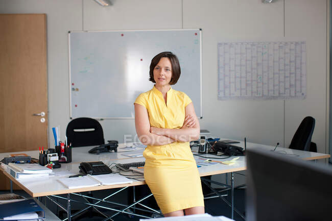 Businesswoman leaning on desk in office — Stock Photo