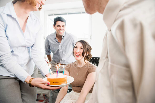 Female office worker receiving birthday cake — Stock Photo