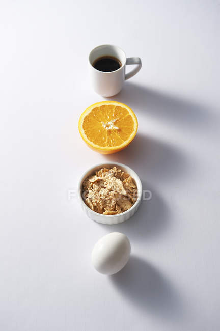 Artículos de desayuno en fila en la superficie blanca - foto de stock