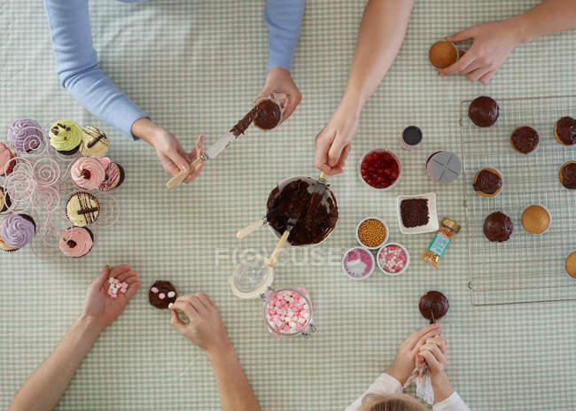 Overhead view of people decorating cakes at table — Stock Photo