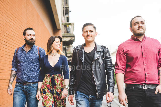 Group of friends walking on sidewalk together — Stock Photo