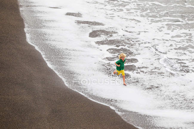 Junge spielt in Wellen am Strand — Stockfoto