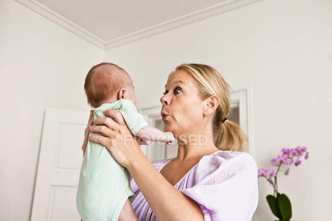 Madre sosteniendo bebé en el dormitorio - foto de stock