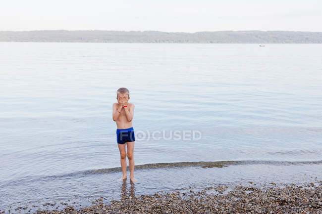 Хлопчик прикриває обличчя на пляжі — стокове фото