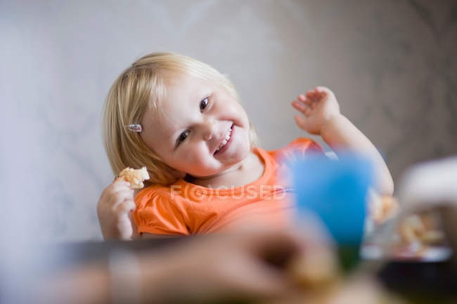 Дівчина Тоддлер посміхається за обіднім столом — стокове фото
