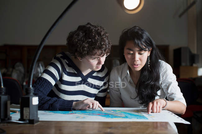 Estudiantes leyendo mapa en clase - foto de stock