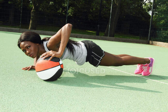 Frau macht Liegestütze auf Basketballplatz — Stockfoto