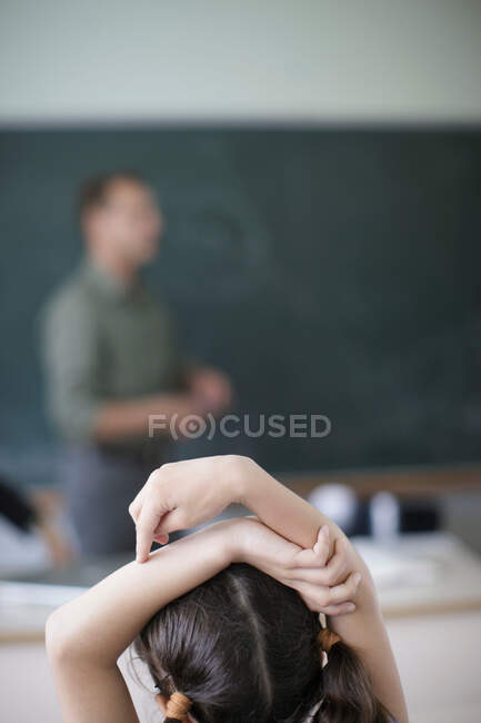 Ragazza della scuola alzando le mani in classe — Foto stock