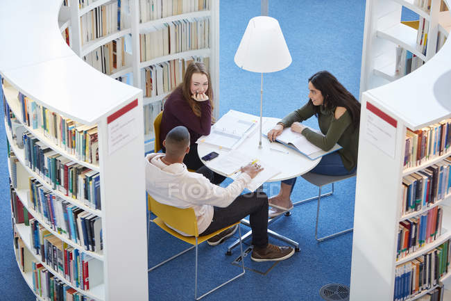 Молодые студенты университета, работающие в библиотеке — стоковое фото
