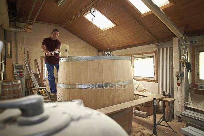 Worker hammering barrel in shop — Stock Photo