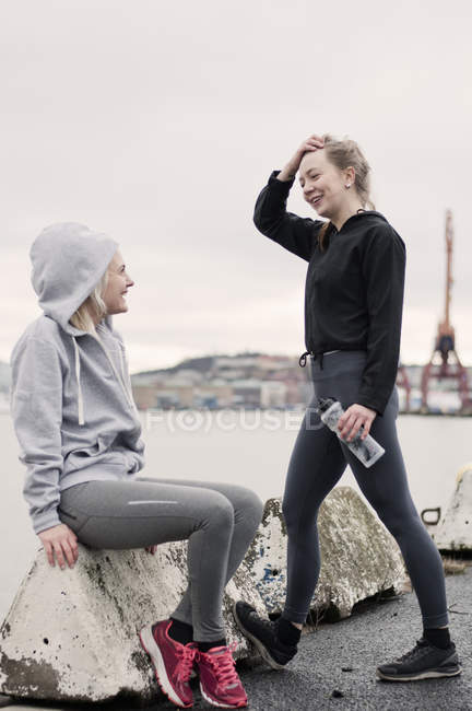 Two female running friends chatting on dockside — Stock Photo