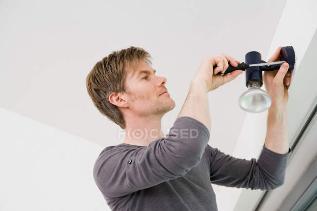Homme installant luminaire dans la maison — Photo de stock