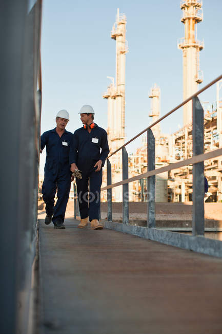 Trabajadores caminando en la refinería de petróleo - foto de stock