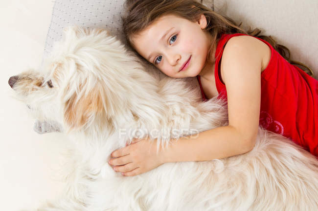 Chica relajante en la cama con el perro - foto de stock