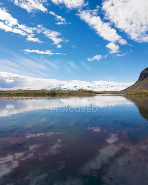 Nuvens e montanhas refletidas no lago — Fotografia de Stock