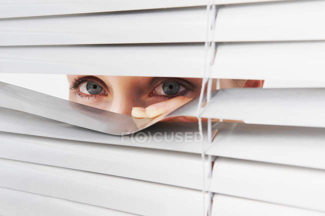Mulher olha através de persianas — Fotografia de Stock