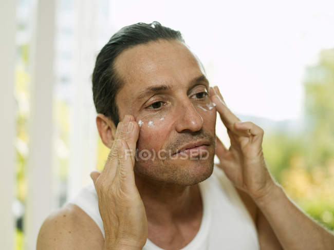 Man applying moisturizer to face, focus on foreground — Stock Photo