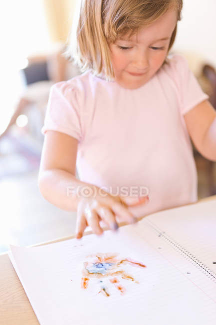 Portrait of Girl finger-painting in notebook — Stock Photo