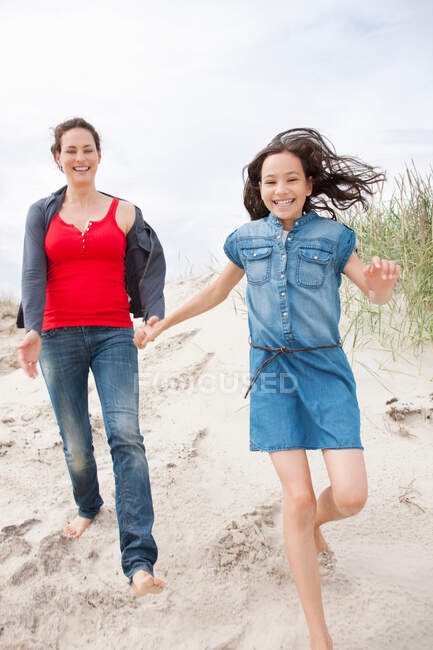 Madre e hija caminando en la playa - foto de stock