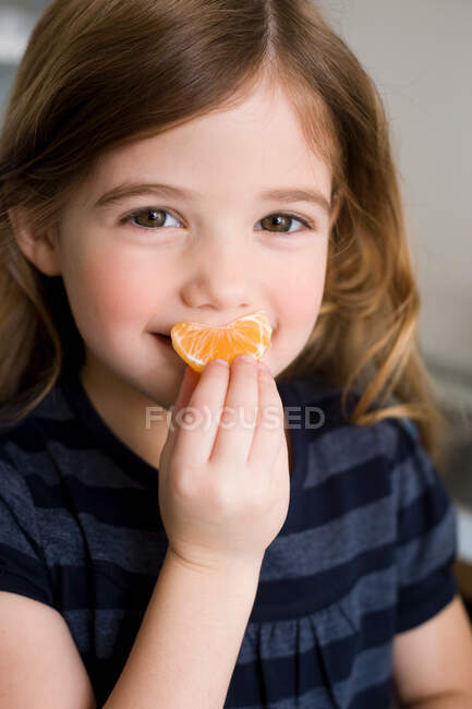 Retrato de niña sosteniendo mandarina - foto de stock