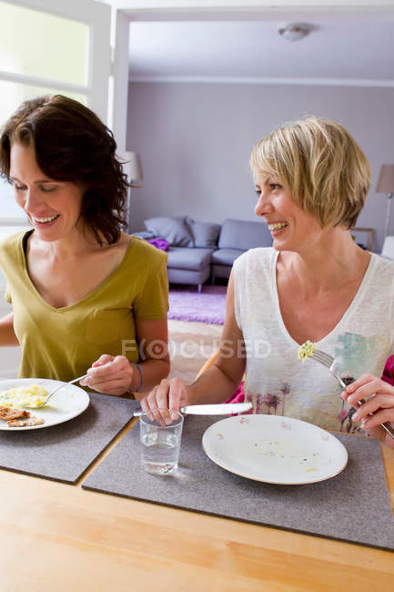 Lächelnde Frauen beim gemeinsamen Mittagessen — Stockfoto