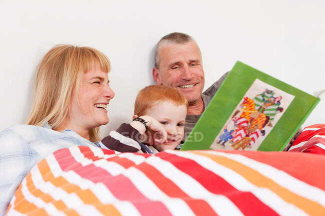 Família livro de leitura juntos na cama — Fotografia de Stock