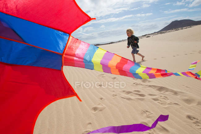 Хлопчик літає повітряним змієм на пляжі — стокове фото