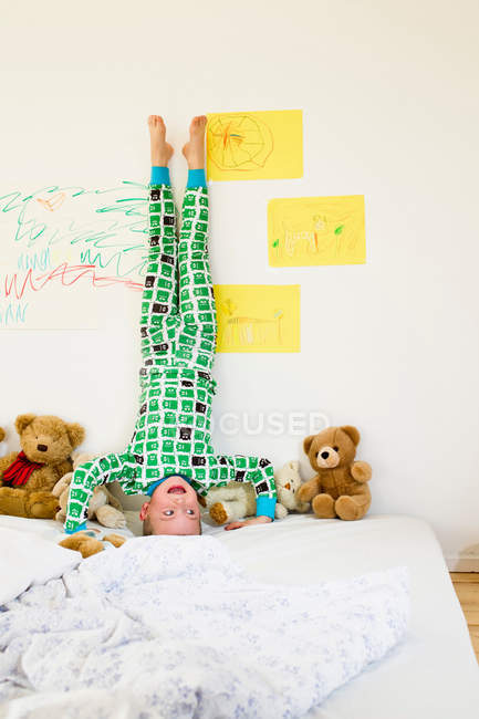Мальчик делает стойку на голове на кровати — стоковое фото